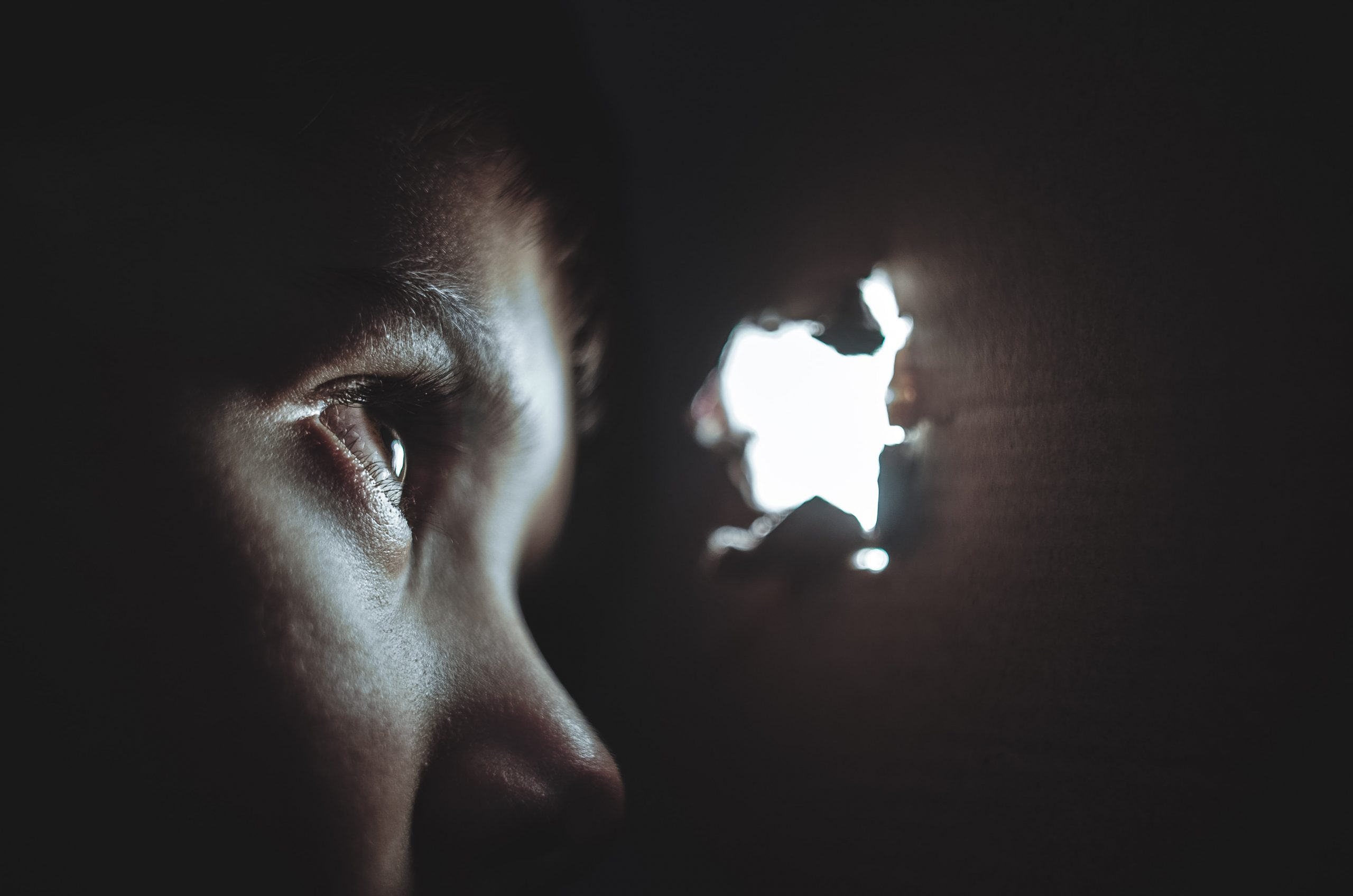 Domestic Violence victim looking through a light hole